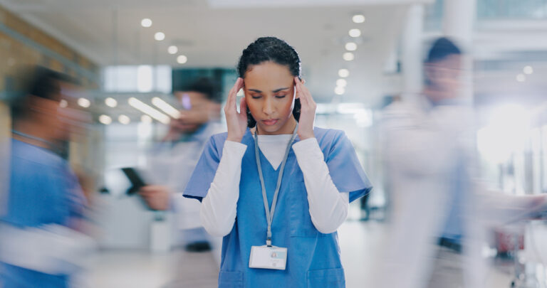 Nurse experiencing burnout in a busy hospital hallway — exploring nurse burnout solutions through technology